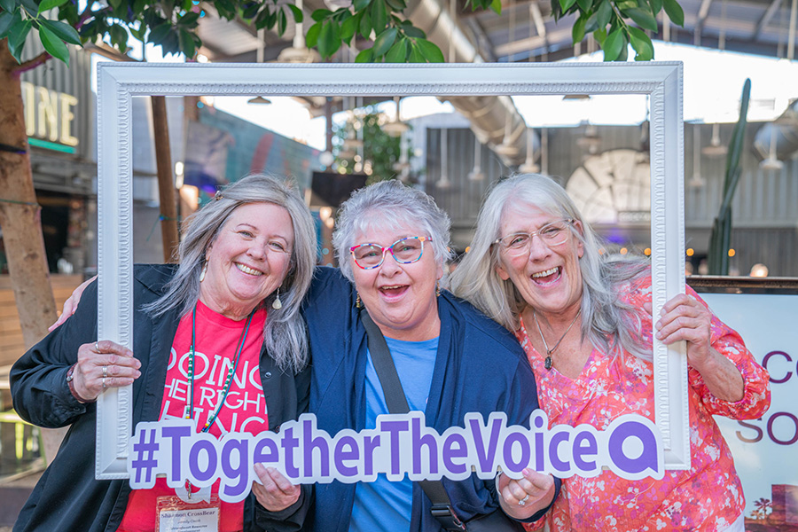Women smiling through a frame with the phrase #togetherthevoice